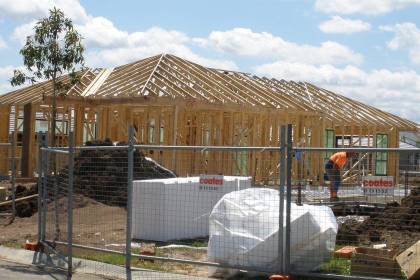 Materials sit behind a fence on a suburban construction site.