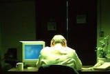 A man sits at a desk with his head in his hands