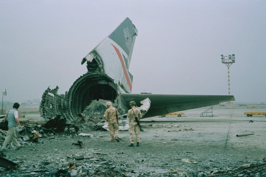 Soldiers stand near the ruins of a passenger plane.