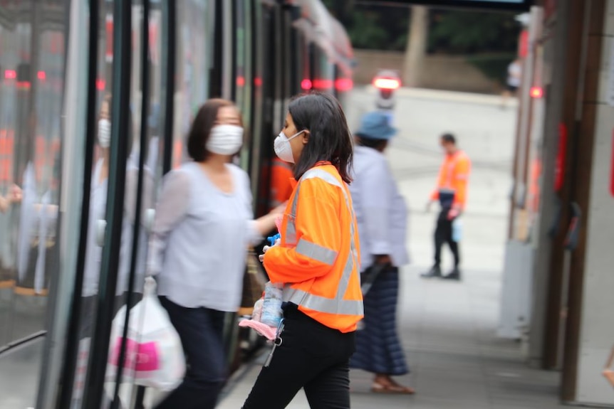 A woman in a mask in a hi-vis long-sleeved shirt