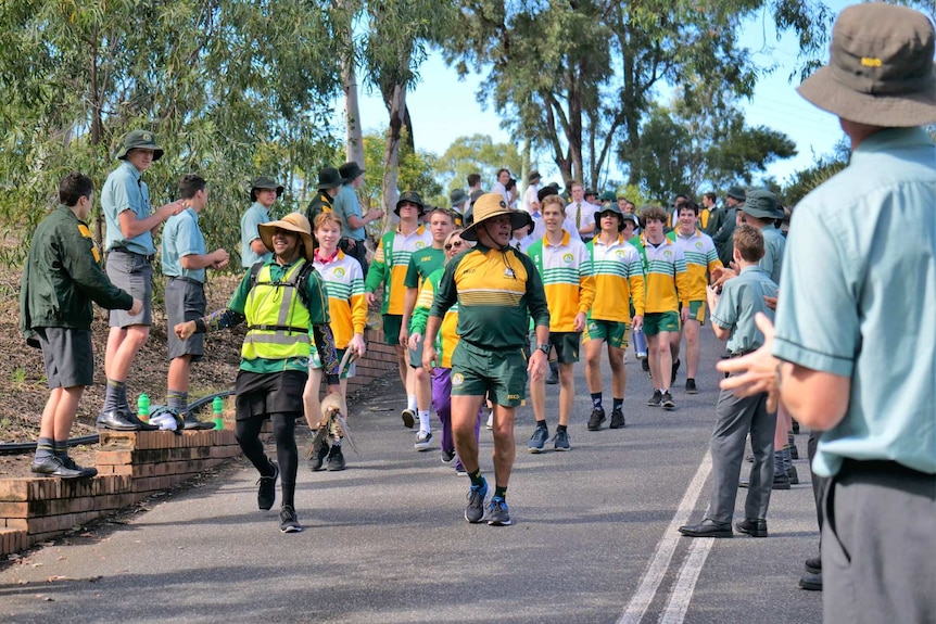 Alwyn Doolan, Peter, Cara and Caleb (Bartlett family members) walk through a guard of honour, students clap and fist bump.