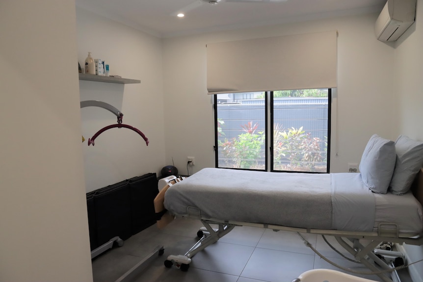 A room with a bed and an air-conditioner can be seen. The room is simple and has hoists above the bed. Ausnew Home Care, NDIS registered provider, My Aged Care