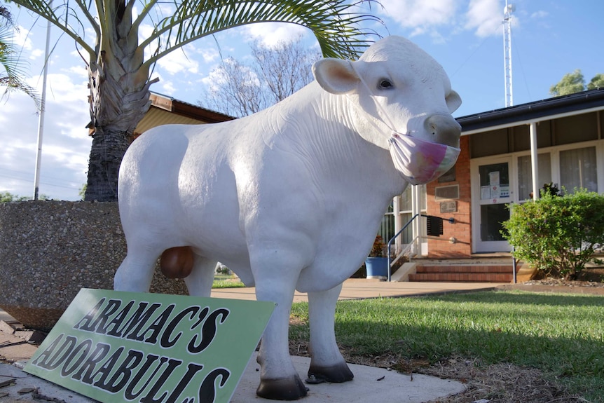A statue of a white bull wearing a face mask.