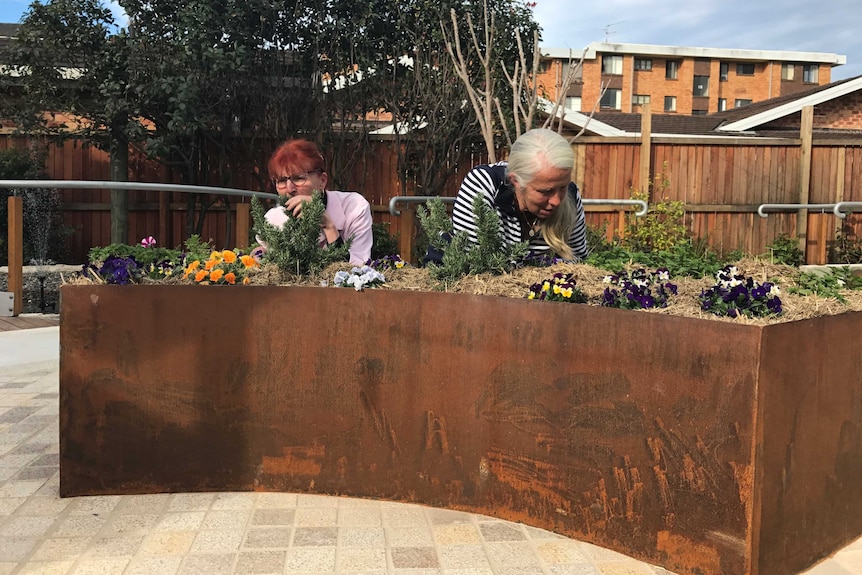 Two women smell herbs at the pick and sniff section of the dementia garden in Port Macquarie