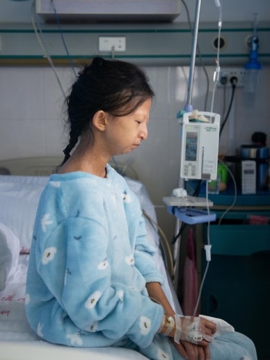 Chinese student Wu Huayan sits on the edge of her bed in hospital.