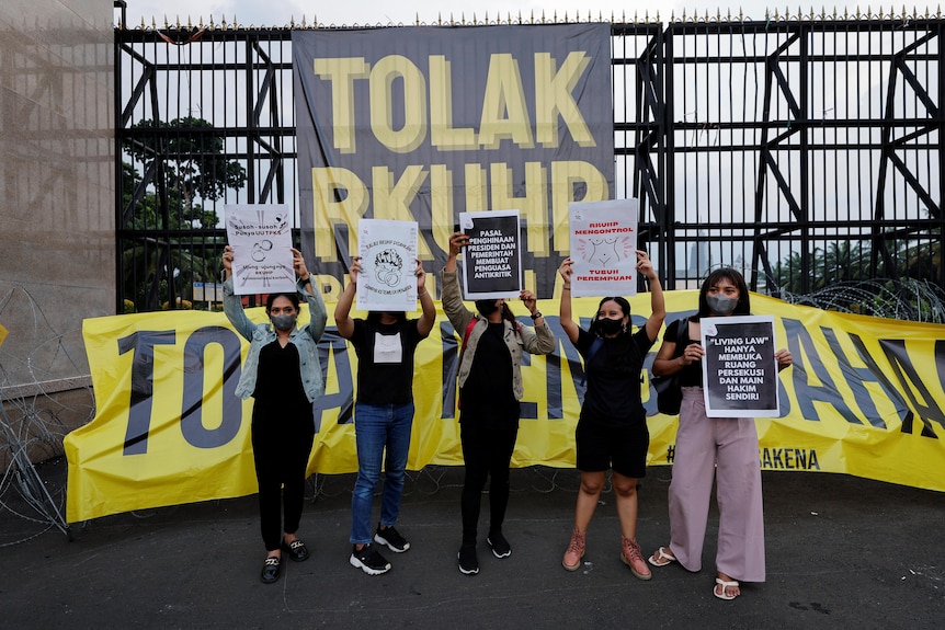 People hold up signs during a protest as Indonesia