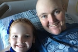 Golfer Jarrod Lyle lies in a hospital bed with his daughter Lusi next to him.