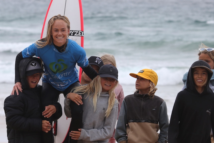 A young woman surfer on the should of fans.