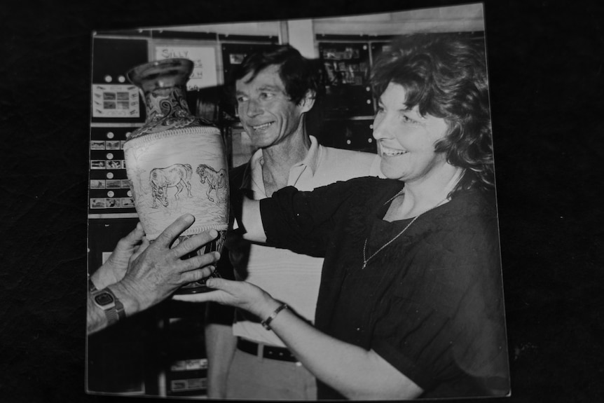 a woman and a man hold an antique vase.