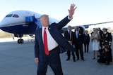 President Donald Trump waves in front of the Boeing 787 Dreamliner