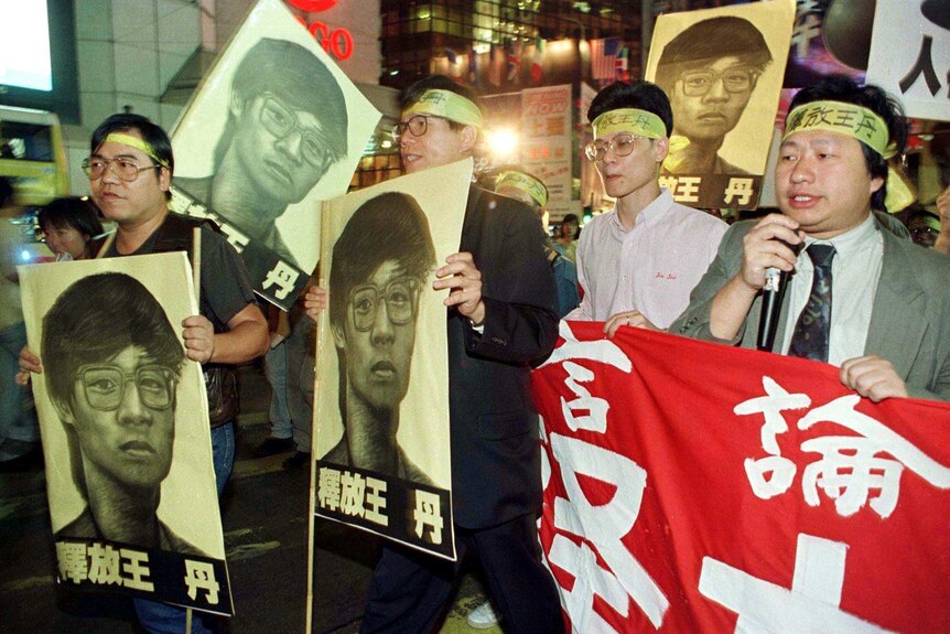 Demonstrators hold banners and portraits of detained Chinese dissident Dan Wang.