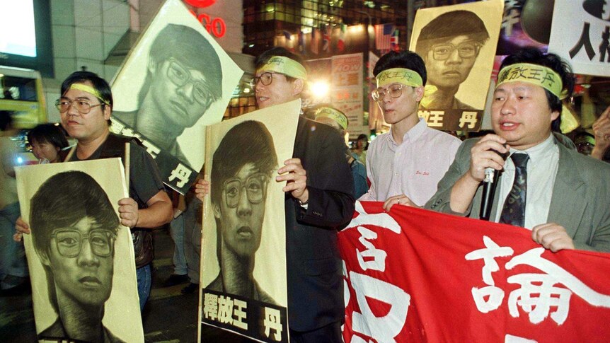 Demonstrators hold banners and portraits of detained Chinese dissident Dan Wang.