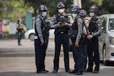 Myanmar police officers stand on a road.