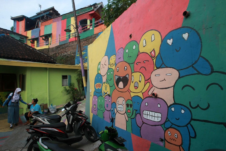 A colourful mural of cartoon characters pulling different faces in Wonosari Village, Indonesia.