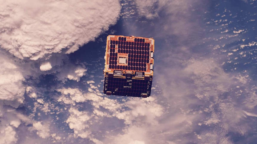 A cube satellite in orbit with earth's atmosphere in the background