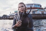 Volunteer Harriet Spark in her snorkelling gear, holding a handful of straws retrieved from the ocean.