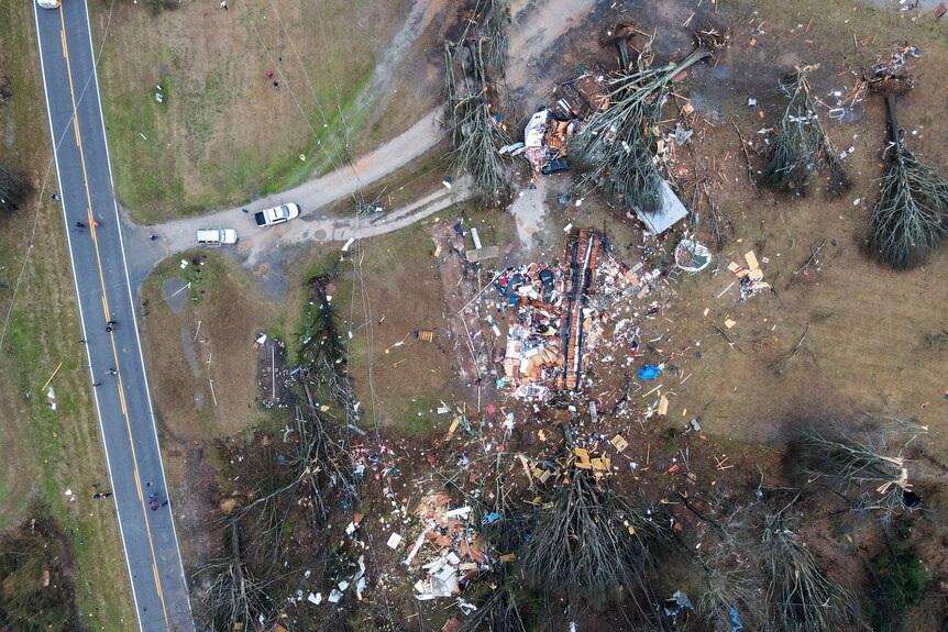 Aerial view of fallen trees and debris on a block of land next to a road