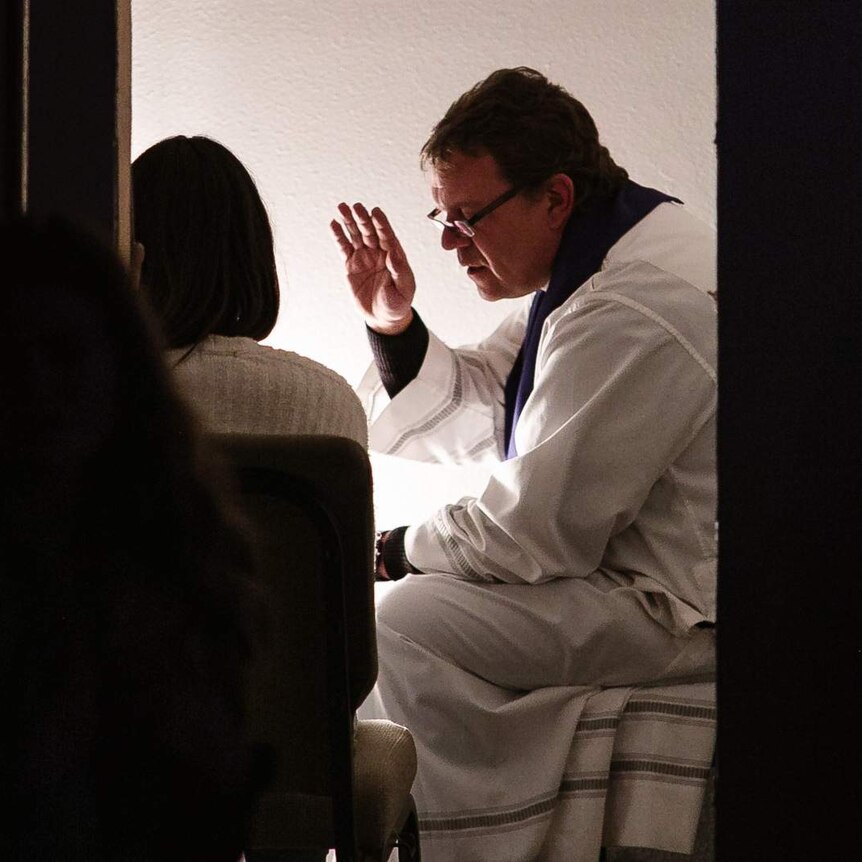 Priest listening to confession from young girl.