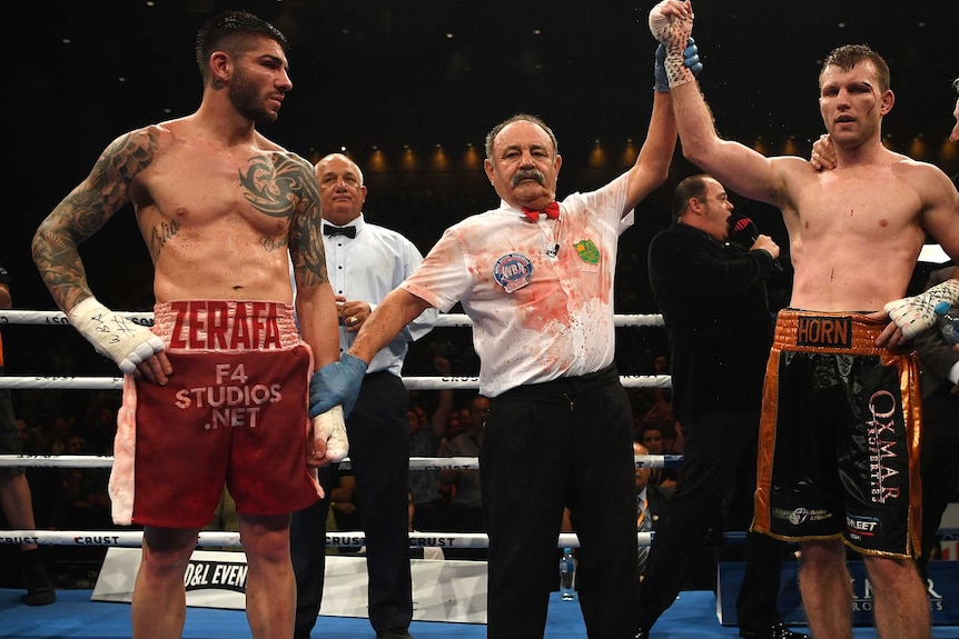 The referee holds Jeff Horn's arm aloft in victory, while fellow boxer Michael Zerafa (left) looks on.