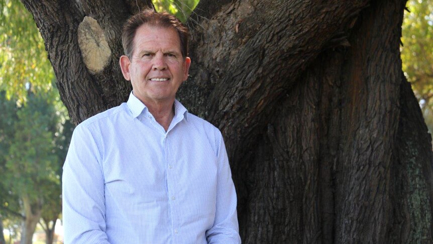 Chris Hatton stands in front of a large tree.