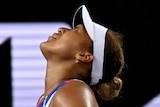 A female tennis player stands with her hands on her hips as she looks up to the sky at the Australian Open.