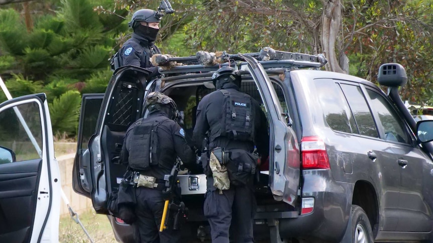 Heavily armed police with masks, near car, with bulletproof vests