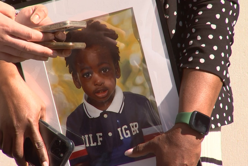 A close up of hands holding a picture of a small boy