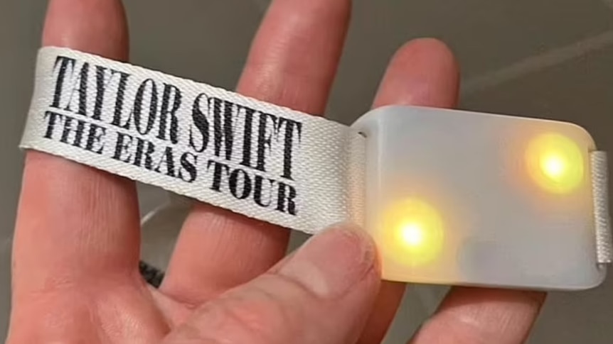 A wristband that reads "Taylor Swift", with a small compartment containing LEDs.