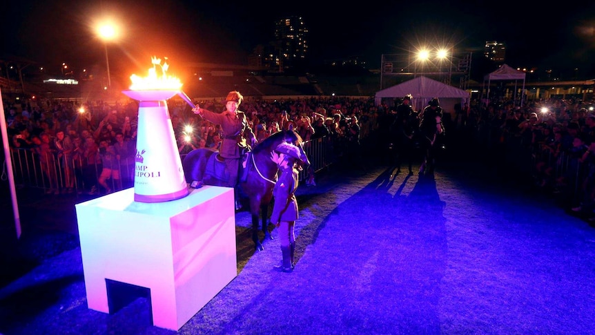 A soldier on horseback lights a torch at a Camp Gallipoli event