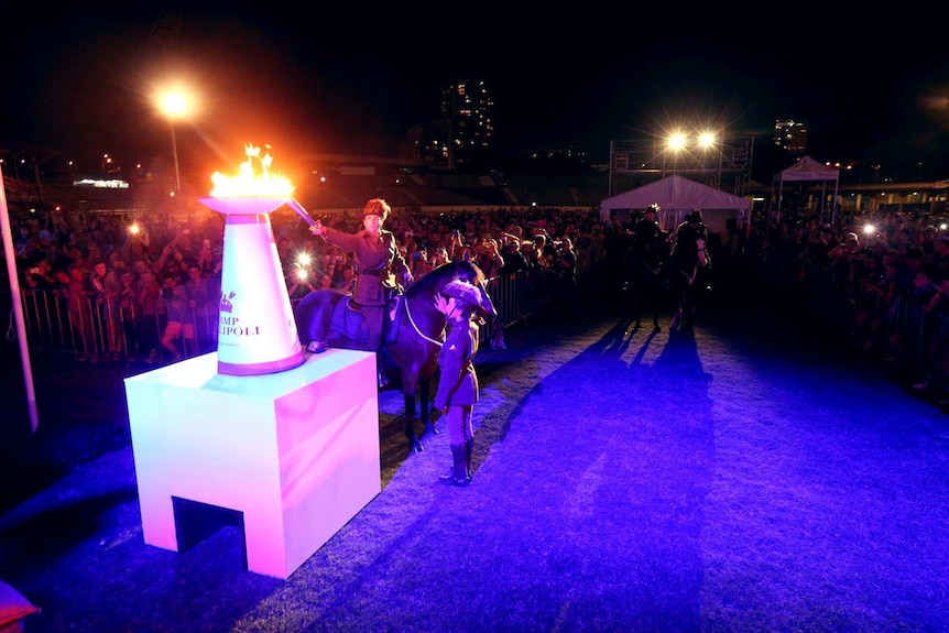 A soldier on horseback lights a torch at a Camp Gallipoli event