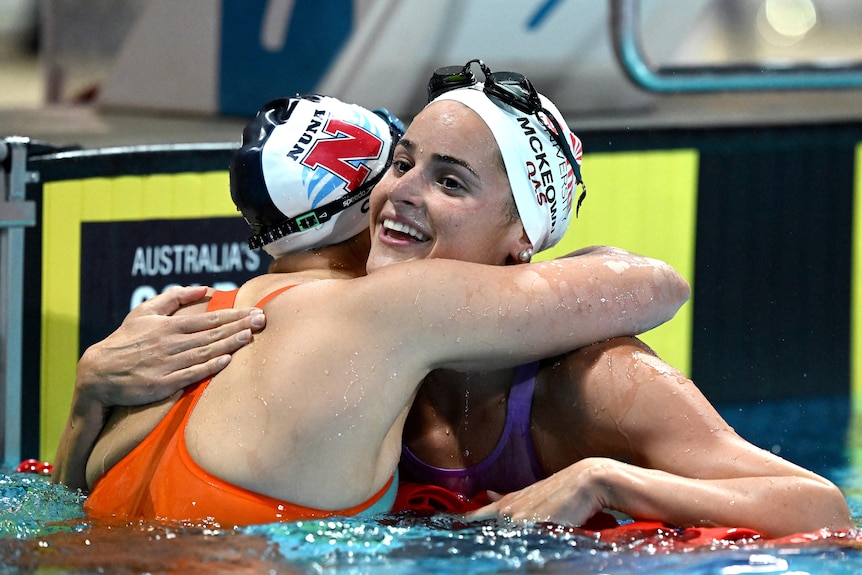 Kaylee McKeown smiles while hugging a competitor after a race across the lane rope