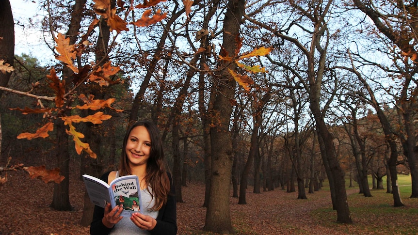 Young woman holding book in the forest