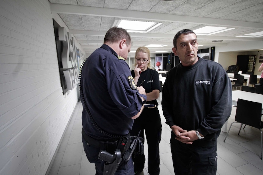 Australian police officer Scott Goodwin addresses workers at a factory.