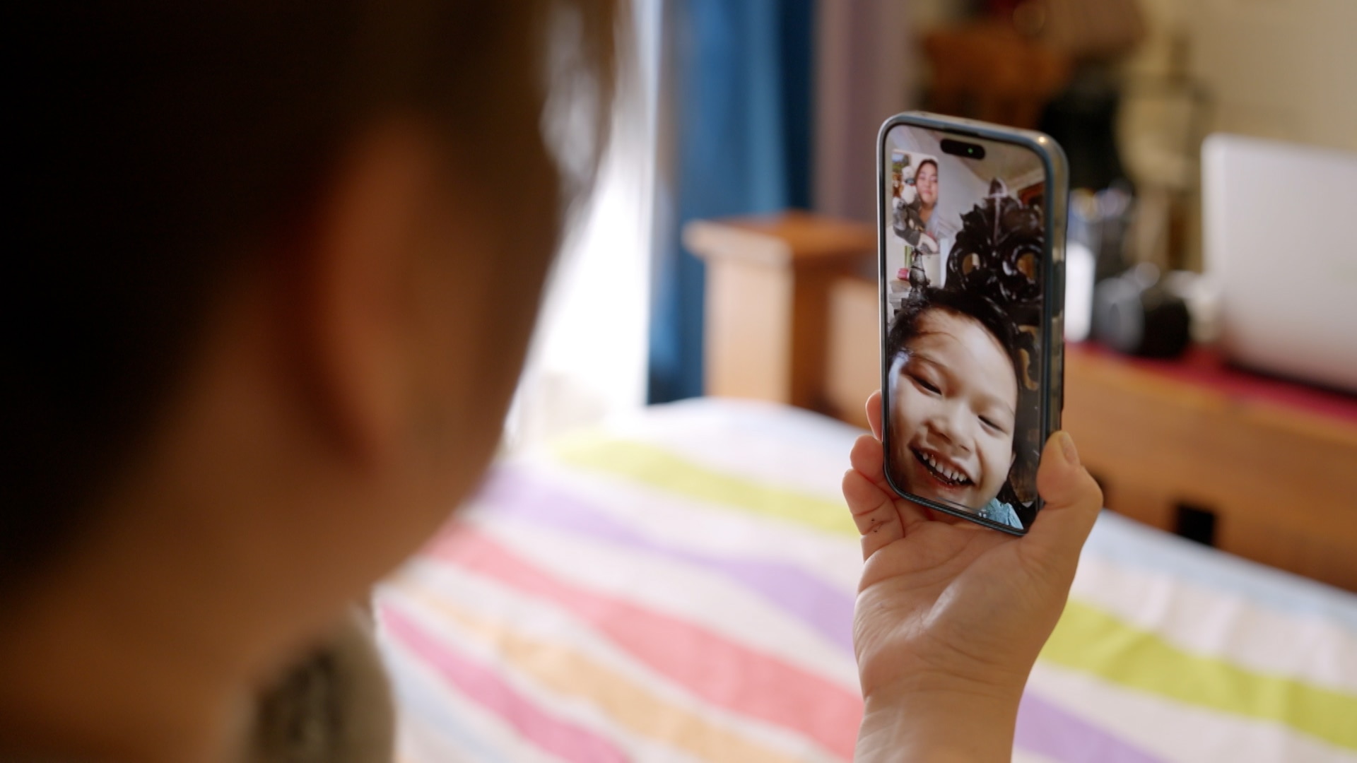 Mother holds phone during video call with her daughter holding up a koala toy to the phone camera