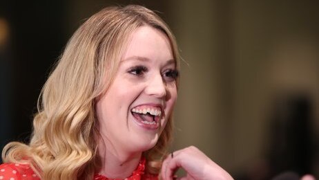 A young woman with blonde hair laughs.