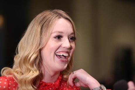 A young woman with blonde hair laughs.