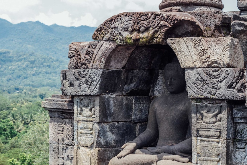 You see a slightly weathered, colossal classical statue of the Buddha nestled in an alcove decorated with with dragons.