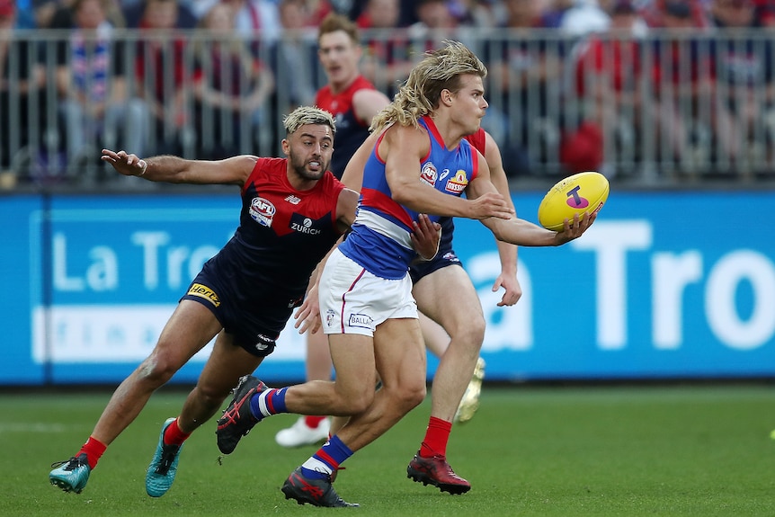 Western Bulldogs' Bailey Smith tries to handball as Melbourne Demons' Christian Salem tackles him.