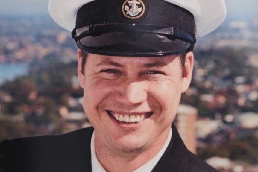 A smiling young man in a Navy uniform.