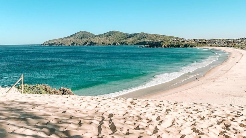 Long beach with blue water and mountains in the background