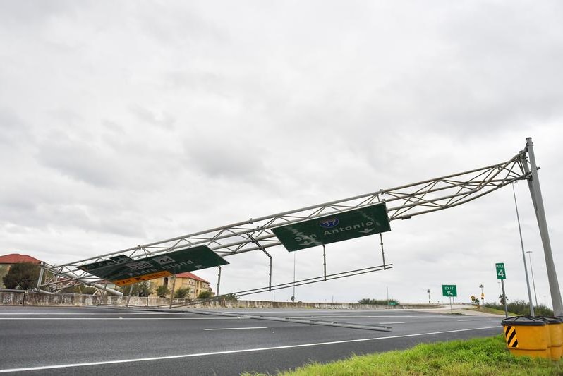 A collapsed overhead gantry lies across the highway
