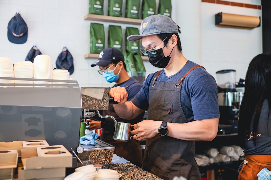 a man wearing a mask making coffee