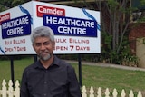 man standing in front of a sign for a healthcare centre