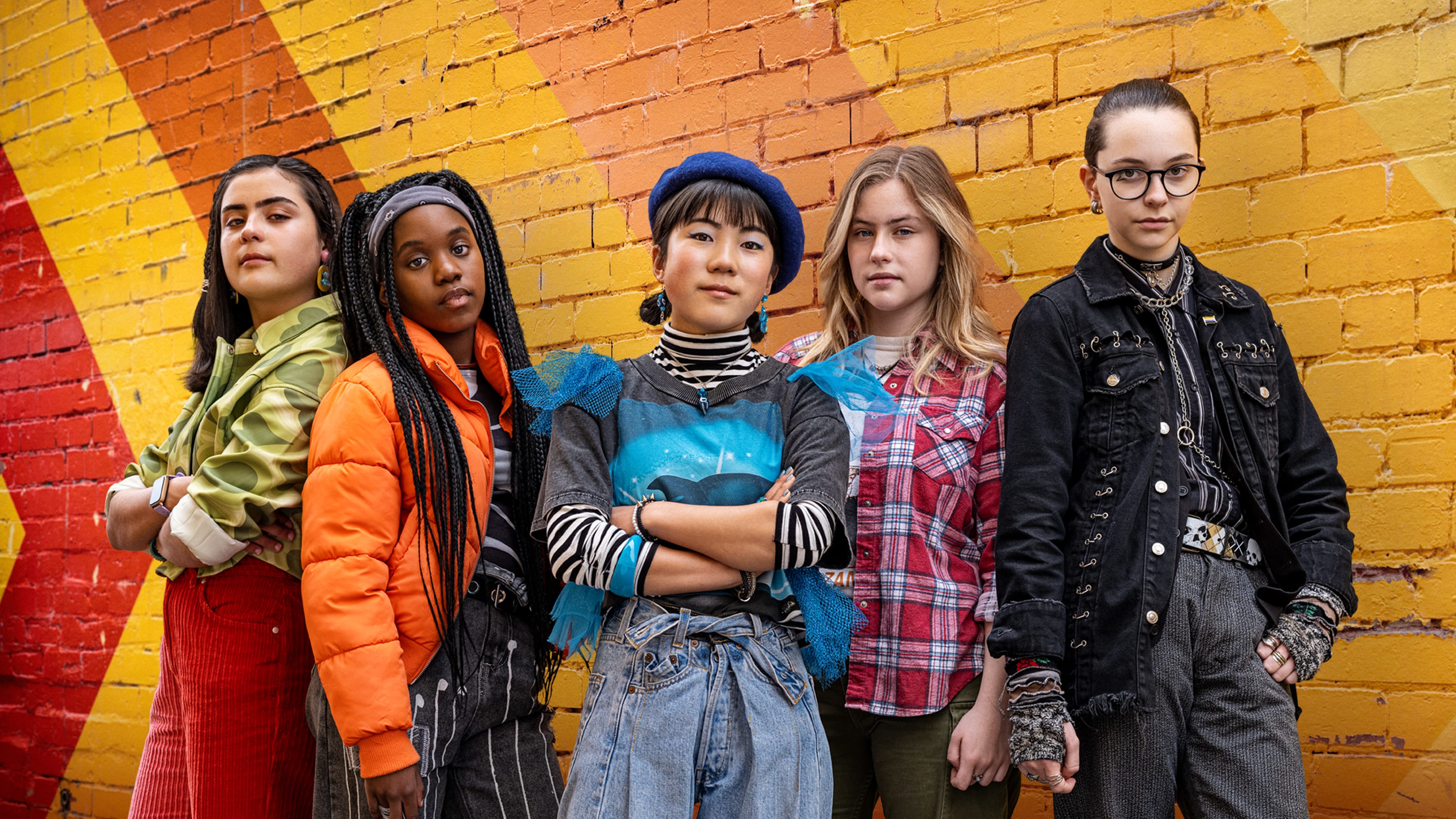 Five teens stand in front of a bright wall with the program title Turn Up The Volume