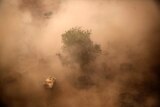 An aerial shot showing a UN vehicle through past red dust and smoke.