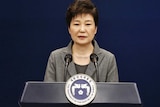 Park Geun-hye at the podium next to the South Korean flag.