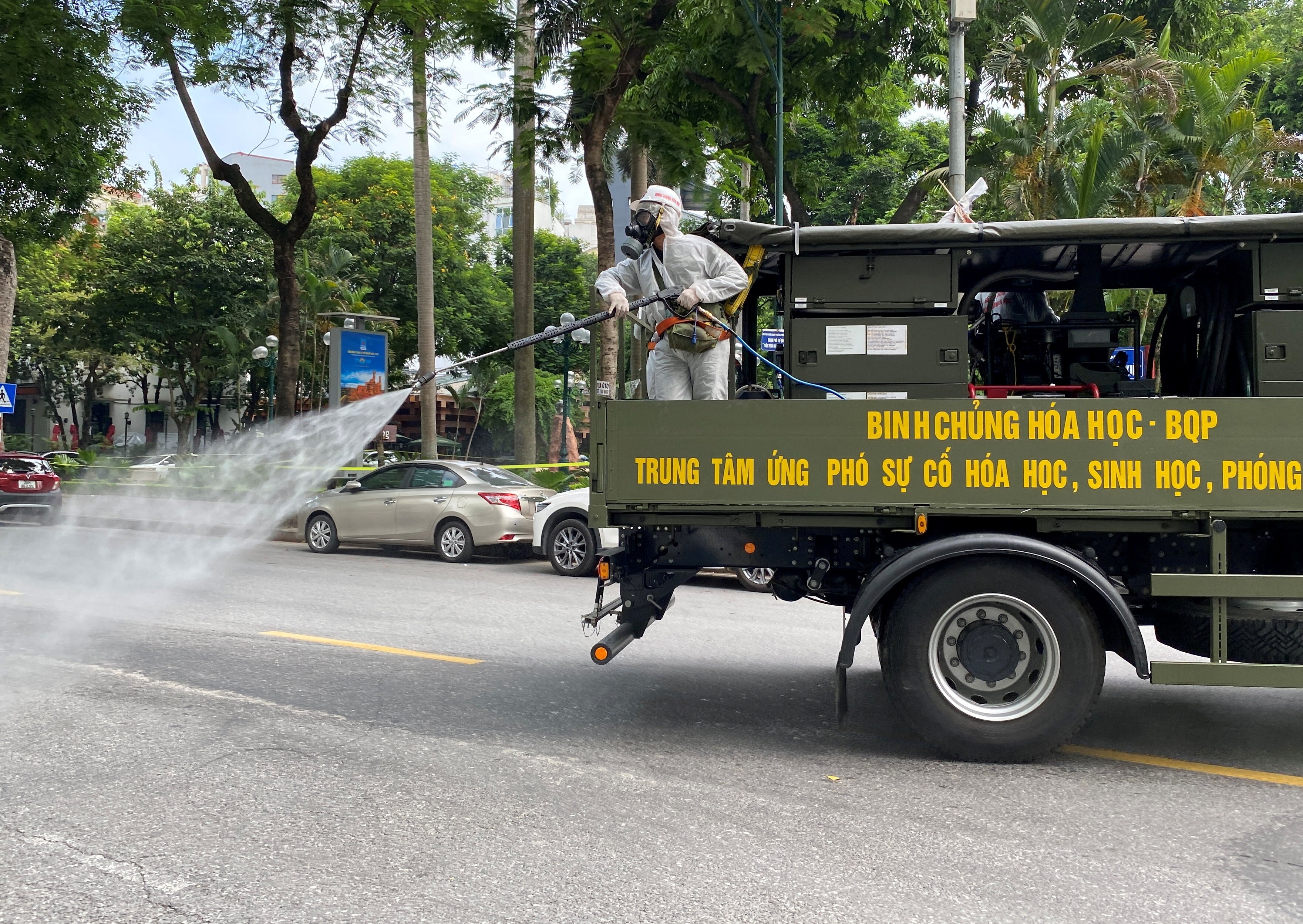 Military personnel wearing PPE spray disinfectant on the streets during a lockdown in Hanoi