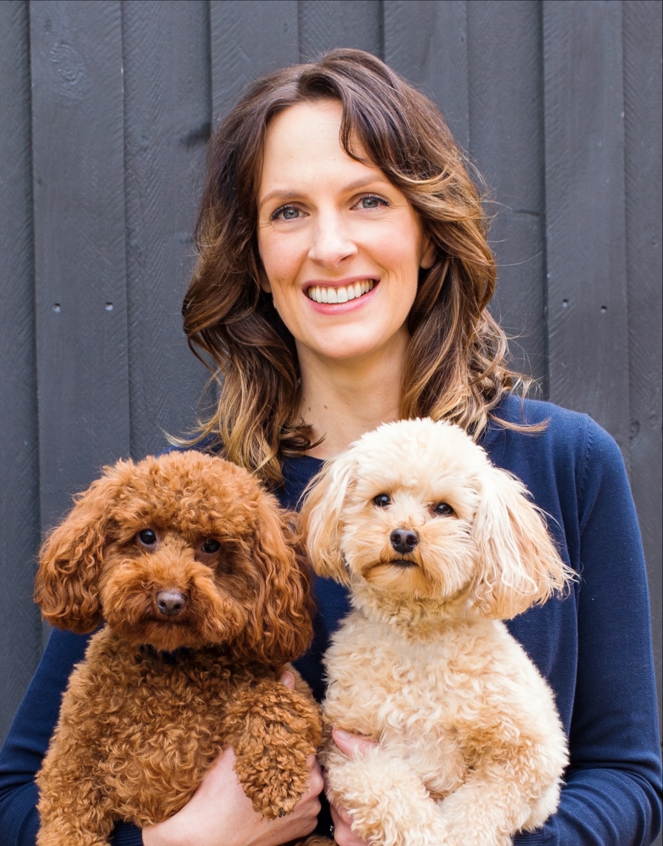 Uma foto de Melissa Meehan segurando dois cavoodles. 