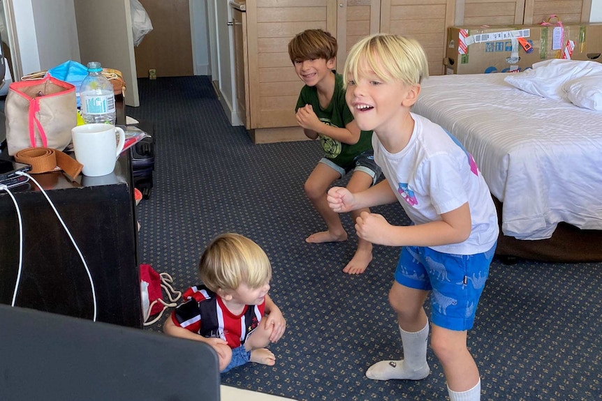 Three young boys follow the moves of an online boot camp, from their hotel room.