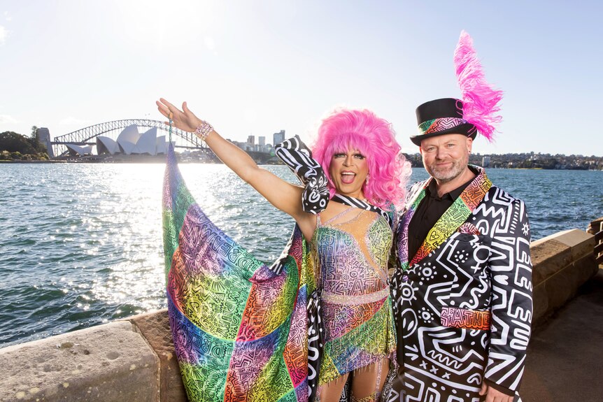Two people dressed in colourful outfits stand in front of Sydney Harbour